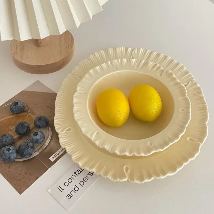 Damian Plate Collection – ceramic plates and bowls with delicate ruffled edges, available in white or cream, combining simple elegance with a soft, feminine touch.