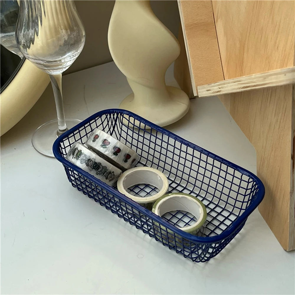 A small, versatile Elon Storage Basket displayed in a minimalist setting. The basket, made of durable metal, comes in butter yellow, sky blue, and navy. It is ideal for various uses, including organizing kitchen essentials, office supplies, or bath accessories. The sleek, utilitarian design complements modern and functional decor. The basket is shown in different color combinations, highlighting its mix-and-match capability for cohesive organization.