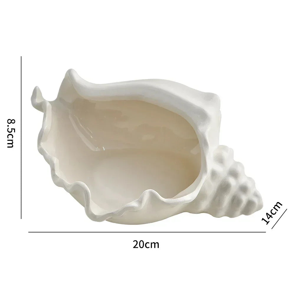 A ceramic Finnegan Shell Tray with a sleek white finish, designed with a delicate shell motif. Ideal for home décor enthusiasts, this versatile tray serves as an elegant accent for organizing jewelry, serving small treats, or as a decorative centerpiece for coastal or minimalist interiors. Perfect for adding a touch of sophistication to vanities, coffee tables, or shelves.