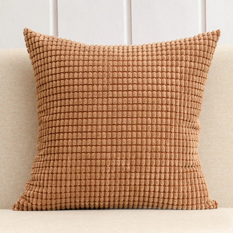 A stylish Warren Pillow Cover displayed on a couch, showcasing its soft corduroy corn grain texture. Available in various colorways and sizes, this square pillow cover adds warmth and elegance to any space. Ideal for home décor enthusiasts, it enhances living areas with a cozy, inviting touch. Please note that the pillow insert is not included.