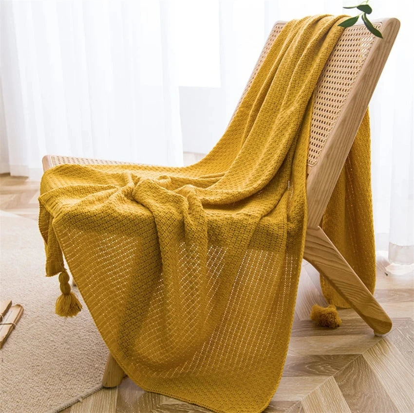 Image of the Soma Throw Blanket, featuring a cozy, soft fleece and cotton blend with a waffled texture. Available in various colorways and three sizes, this throw blanket has elegant tasseled corners and a knitted design, perfect for home décor enthusiasts looking to add comfort and style to their living space.
