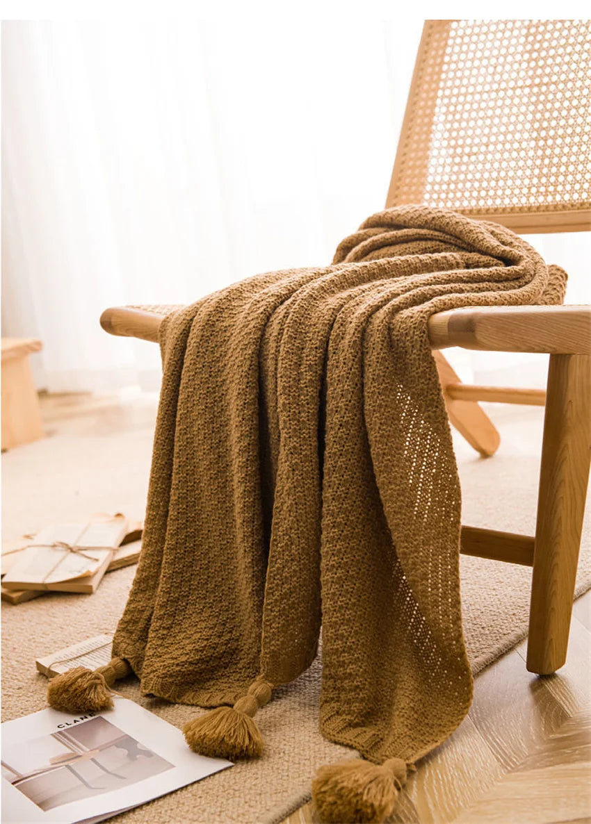 Image of the Soma Throw Blanket, featuring a cozy, soft fleece and cotton blend with a waffled texture. Available in various colorways and three sizes, this throw blanket has elegant tasseled corners and a knitted design, perfect for home décor enthusiasts looking to add comfort and style to their living space.