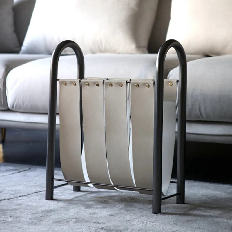 Hazel Magazine Rack featuring a modern metal frame with leather straps, available in black, white, or brown. Comes in small or large sizes to suit different spaces. Perfect for organizing and displaying magazines, books, or newspapers in a stylish and functional way. Designed for home décor enthusiasts who appreciate sleek, minimalist storage solutions that add elegance to living rooms, offices, or bedrooms.
