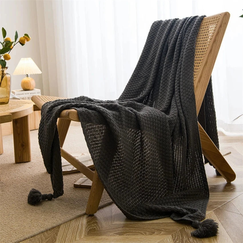 Image of the Soma Throw Blanket, featuring a cozy, soft fleece and cotton blend with a waffled texture. Available in various colorways and three sizes, this throw blanket has elegant tasseled corners and a knitted design, perfect for home décor enthusiasts looking to add comfort and style to their living space.