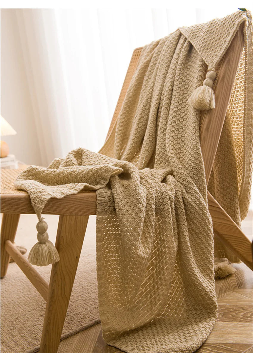 Image of the Soma Throw Blanket, featuring a cozy, soft fleece and cotton blend with a waffled texture. Available in various colorways and three sizes, this throw blanket has elegant tasseled corners and a knitted design, perfect for home décor enthusiasts looking to add comfort and style to their living space.