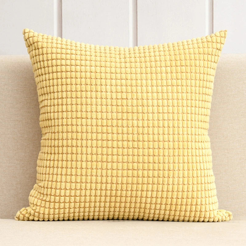 A stylish Warren Pillow Cover displayed on a couch, showcasing its soft corduroy corn grain texture. Available in various colorways and sizes, this square pillow cover adds warmth and elegance to any space. Ideal for home décor enthusiasts, it enhances living areas with a cozy, inviting touch. Please note that the pillow insert is not included.