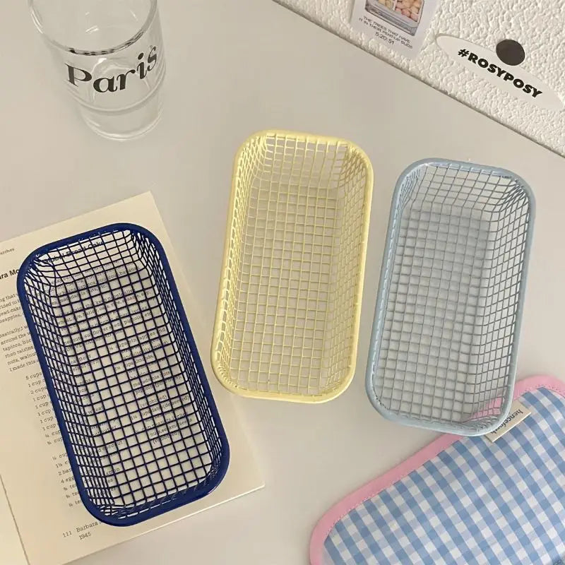 A small, versatile Elon Storage Basket displayed in a minimalist setting. The basket, made of durable metal, comes in butter yellow, sky blue, and navy. It is ideal for various uses, including organizing kitchen essentials, office supplies, or bath accessories. The sleek, utilitarian design complements modern and functional decor. The basket is shown in different color combinations, highlighting its mix-and-match capability for cohesive organization.