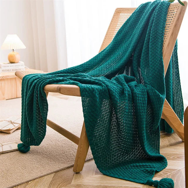 Image of the Soma Throw Blanket, featuring a cozy, soft fleece and cotton blend with a waffled texture. Available in various colorways and three sizes, this throw blanket has elegant tasseled corners and a knitted design, perfect for home décor enthusiasts looking to add comfort and style to their living space.