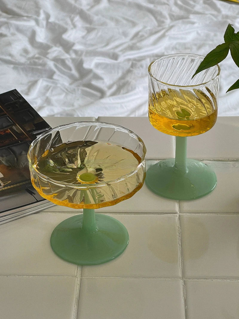 Mayer Glass Collection featuring wine glasses and champagne coupes with elegant fluted design. The bases are available in jade or cream colors. Made from heat-resistant glass, these versatile pieces are perfect for enjoying wine or champagne. Ideal for home décor enthusiasts seeking stylish and functional glassware.