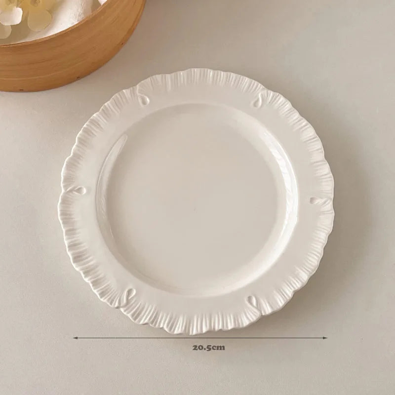 Damian Plate Collection – ceramic plates and bowls with delicate ruffled edges, available in white or cream, combining simple elegance with a soft, feminine touch.