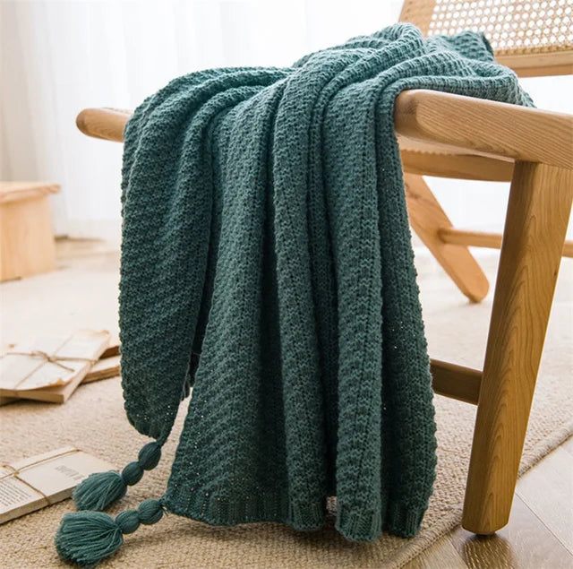 Image of the Soma Throw Blanket, featuring a cozy, soft fleece and cotton blend with a waffled texture. Available in various colorways and three sizes, this throw blanket has elegant tasseled corners and a knitted design, perfect for home décor enthusiasts looking to add comfort and style to their living space.