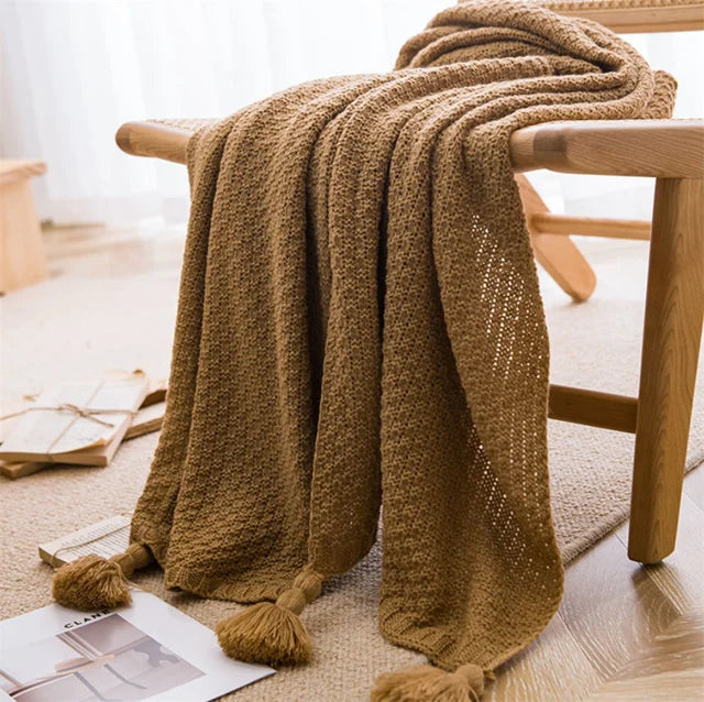 Image of the Soma Throw Blanket, featuring a cozy, soft fleece and cotton blend with a waffled texture. Available in various colorways and three sizes, this throw blanket has elegant tasseled corners and a knitted design, perfect for home décor enthusiasts looking to add comfort and style to their living space.