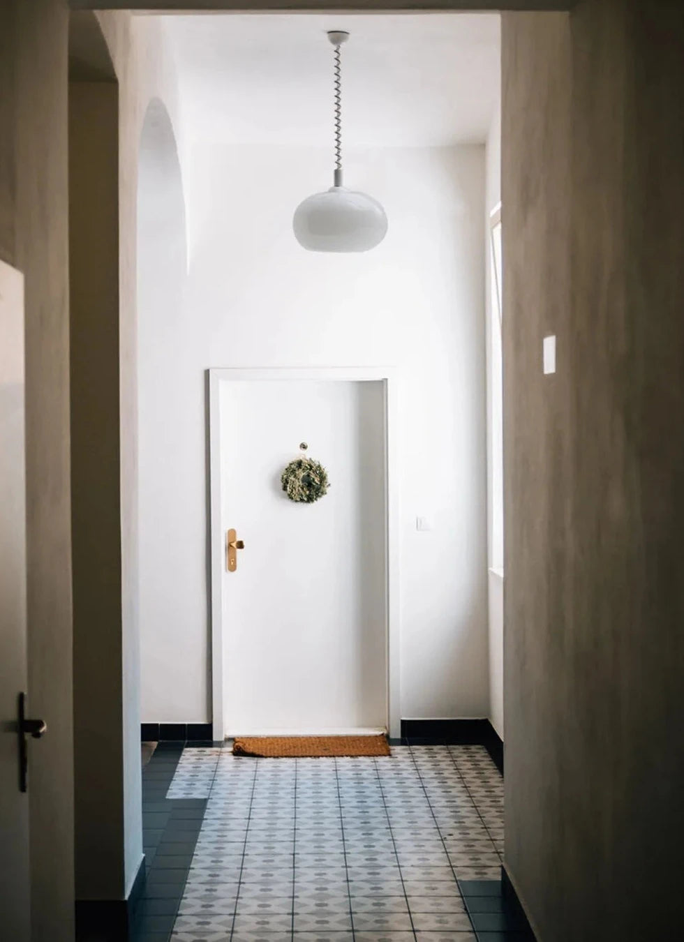 Modern Toz Pendant Light with hand-blown milkglass shade, colored coiled cord in primary colors, and adjustable length.