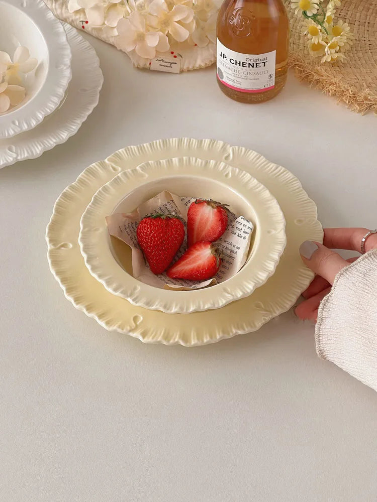 Damian Plate Collection – ceramic plates and bowls with delicate ruffled edges, available in white or cream, combining simple elegance with a soft, feminine touch.