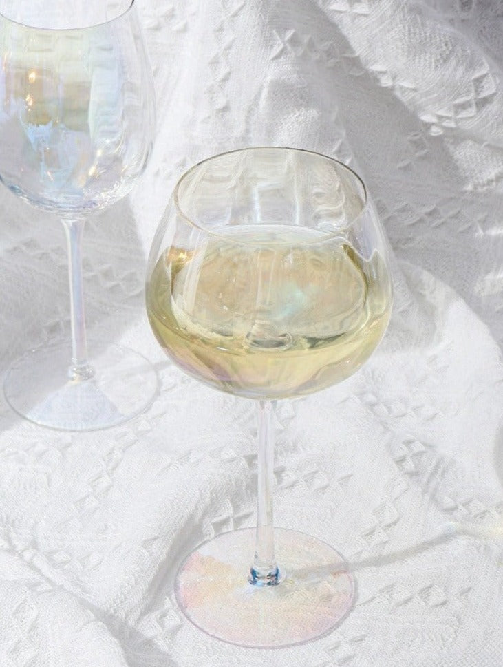 A collection of iridescent glassware from Domus Forge, featuring wine glasses, champagne coupes, decanters, and highball glasses in pastel gradient hues.