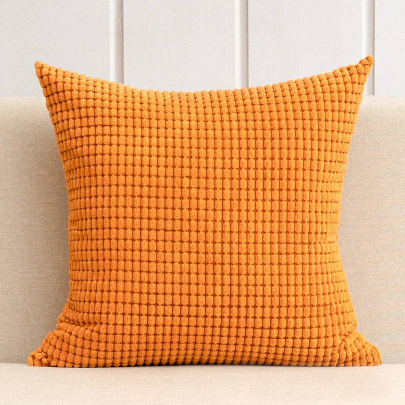 A stylish Warren Pillow Cover displayed on a couch, showcasing its soft corduroy corn grain texture. Available in various colorways and sizes, this square pillow cover adds warmth and elegance to any space. Ideal for home décor enthusiasts, it enhances living areas with a cozy, inviting touch. Please note that the pillow insert is not included.