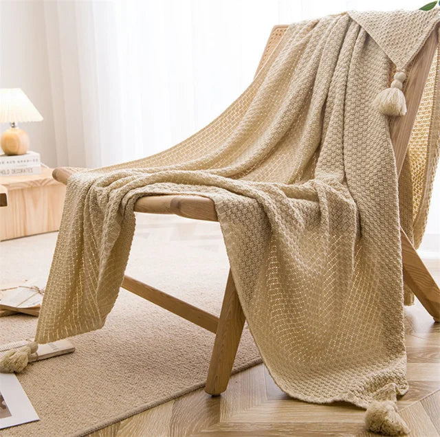 Image of the Soma Throw Blanket, featuring a cozy, soft fleece and cotton blend with a waffled texture. Available in various colorways and three sizes, this throw blanket has elegant tasseled corners and a knitted design, perfect for home décor enthusiasts looking to add comfort and style to their living space.