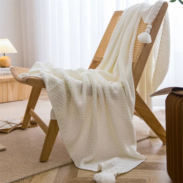 Image of the Soma Throw Blanket, featuring a cozy, soft fleece and cotton blend with a waffled texture. Available in various colorways and three sizes, this throw blanket has elegant tasseled corners and a knitted design, perfect for home décor enthusiasts looking to add comfort and style to their living space.