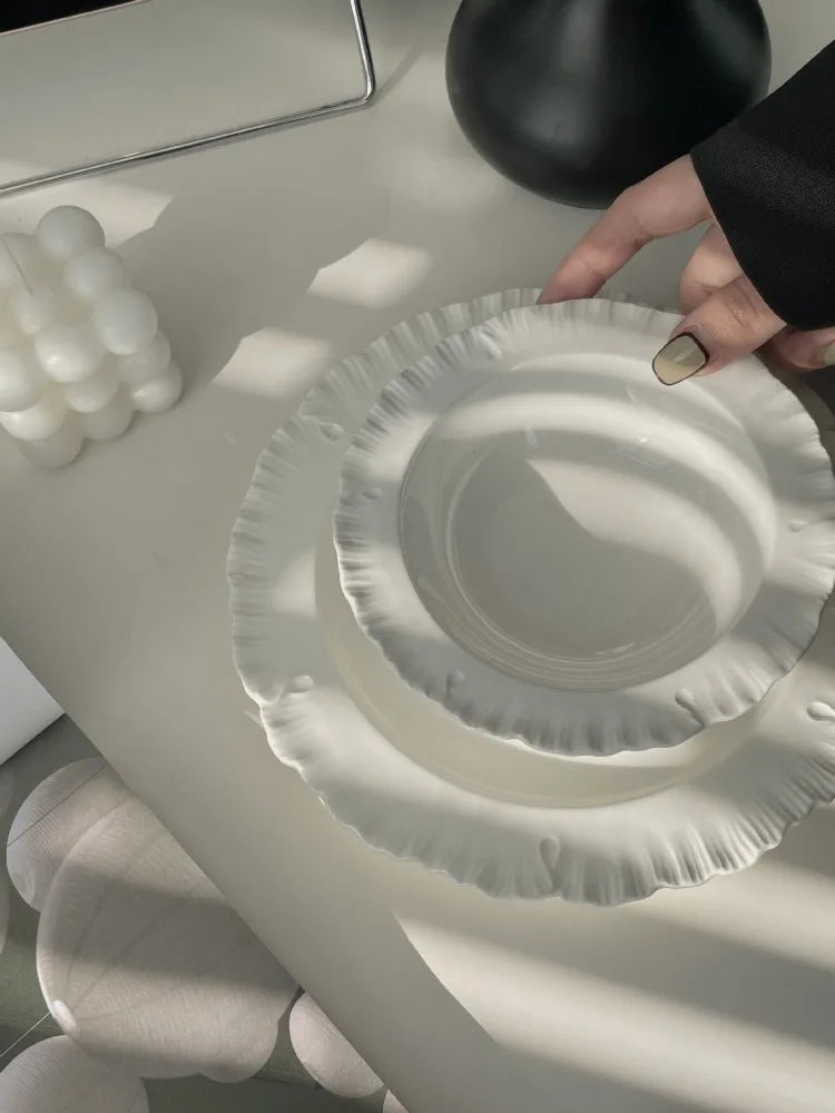 Damian Plate Collection – ceramic plates and bowls with delicate ruffled edges, available in white or cream, combining simple elegance with a soft, feminine touch.