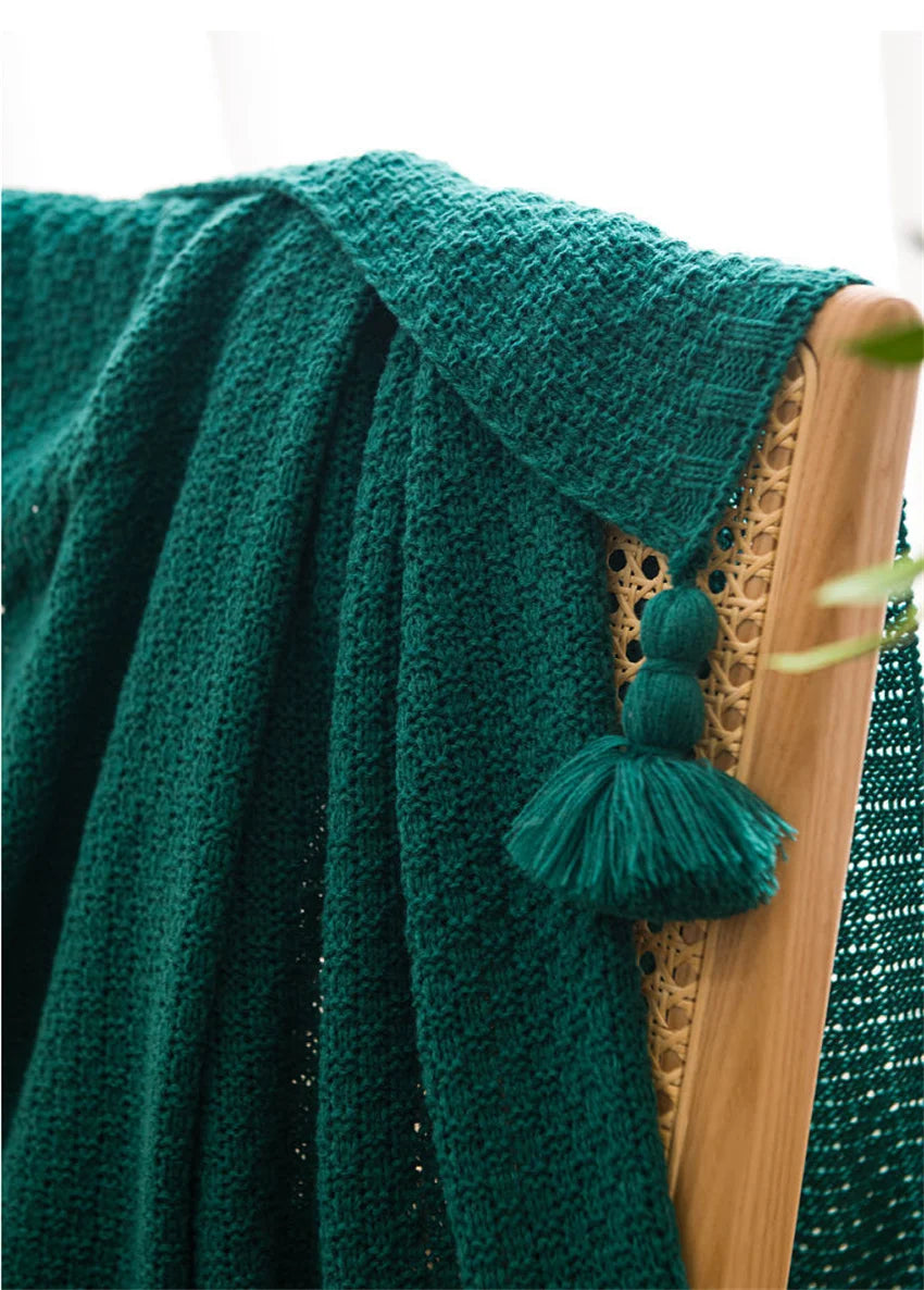 Image of the Soma Throw Blanket, featuring a cozy, soft fleece and cotton blend with a waffled texture. Available in various colorways and three sizes, this throw blanket has elegant tasseled corners and a knitted design, perfect for home décor enthusiasts looking to add comfort and style to their living space.