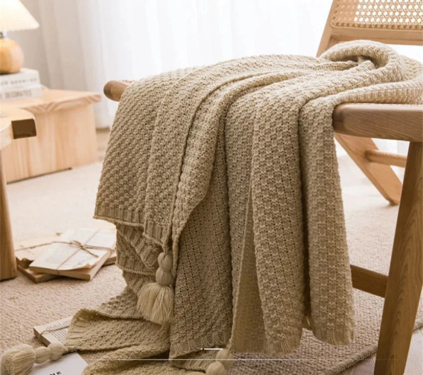 Image of the Soma Throw Blanket, featuring a cozy, soft fleece and cotton blend with a waffled texture. Available in various colorways and three sizes, this throw blanket has elegant tasseled corners and a knitted design, perfect for home décor enthusiasts looking to add comfort and style to their living space.