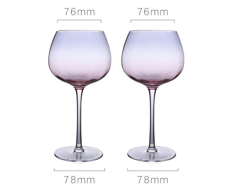 A collection of iridescent glassware from Domus Forge, featuring wine glasses, champagne coupes, decanters, and highball glasses in pastel gradient hues.