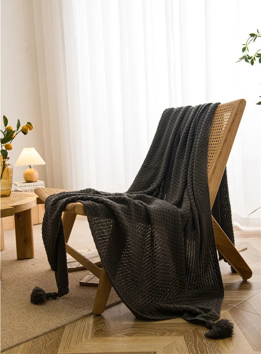 Image of the Soma Throw Blanket, featuring a cozy, soft fleece and cotton blend with a waffled texture. Available in various colorways and three sizes, this throw blanket has elegant tasseled corners and a knitted design, perfect for home décor enthusiasts looking to add comfort and style to their living space.