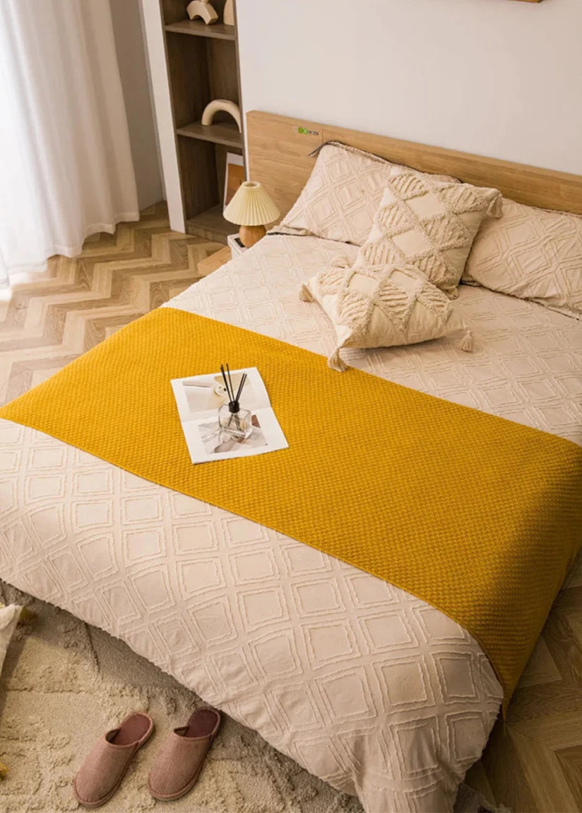 Image of the Soma Throw Blanket, featuring a cozy, soft fleece and cotton blend with a waffled texture. Available in various colorways and three sizes, this throw blanket has elegant tasseled corners and a knitted design, perfect for home décor enthusiasts looking to add comfort and style to their living space.