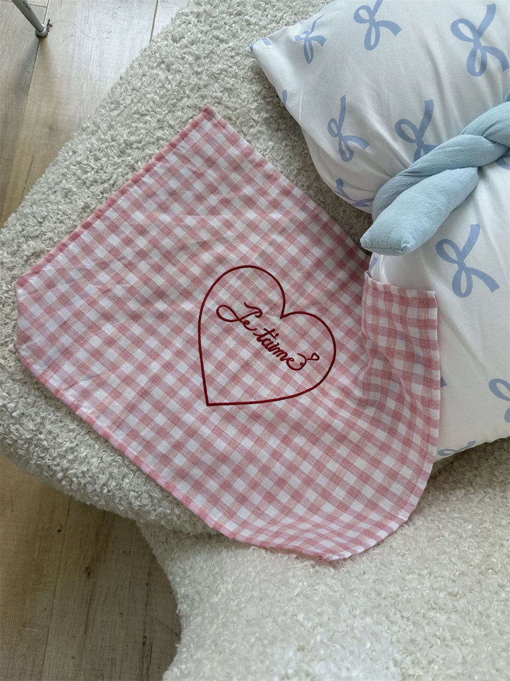 A checkered placemat available in blue or pink, featuring red "je t'aime" embroidery along one edge. Made of soft cotton gauze, the placemat has a vintage, French-inspired charm and measures 30 x 40 cm. Ideal for home decor enthusiasts adding a nostalgic, romantic touch to their dining table.