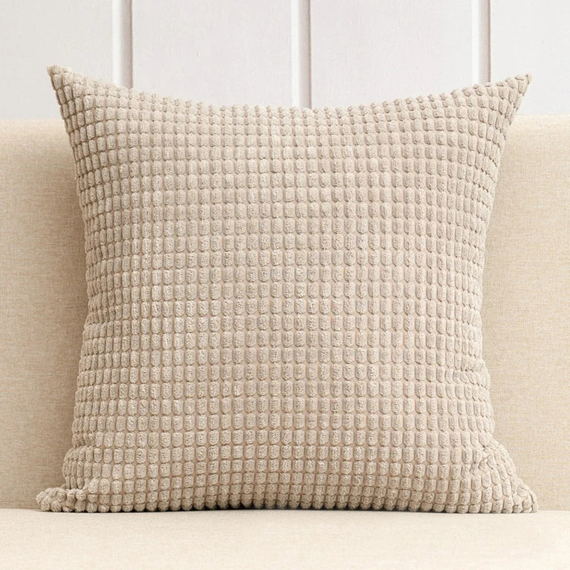 A stylish Warren Pillow Cover displayed on a couch, showcasing its soft corduroy corn grain texture. Available in various colorways and sizes, this square pillow cover adds warmth and elegance to any space. Ideal for home décor enthusiasts, it enhances living areas with a cozy, inviting touch. Please note that the pillow insert is not included.