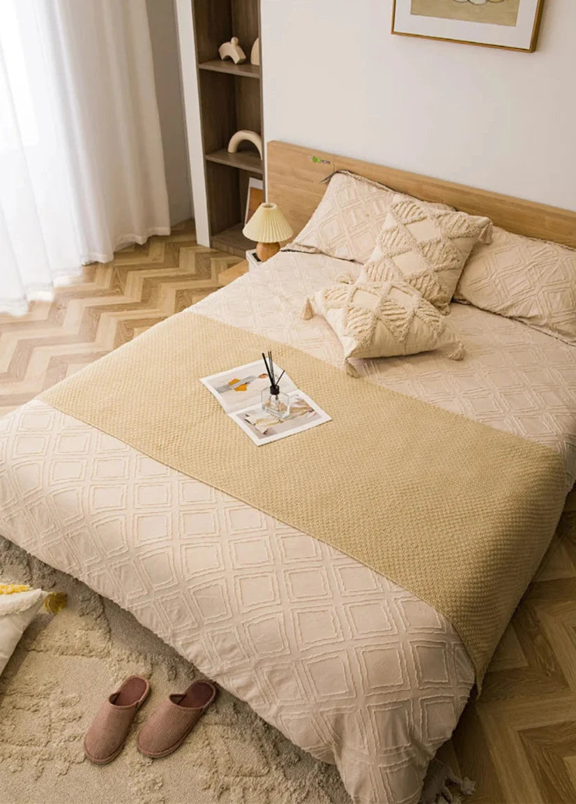 Image of the Soma Throw Blanket, featuring a cozy, soft fleece and cotton blend with a waffled texture. Available in various colorways and three sizes, this throw blanket has elegant tasseled corners and a knitted design, perfect for home décor enthusiasts looking to add comfort and style to their living space.