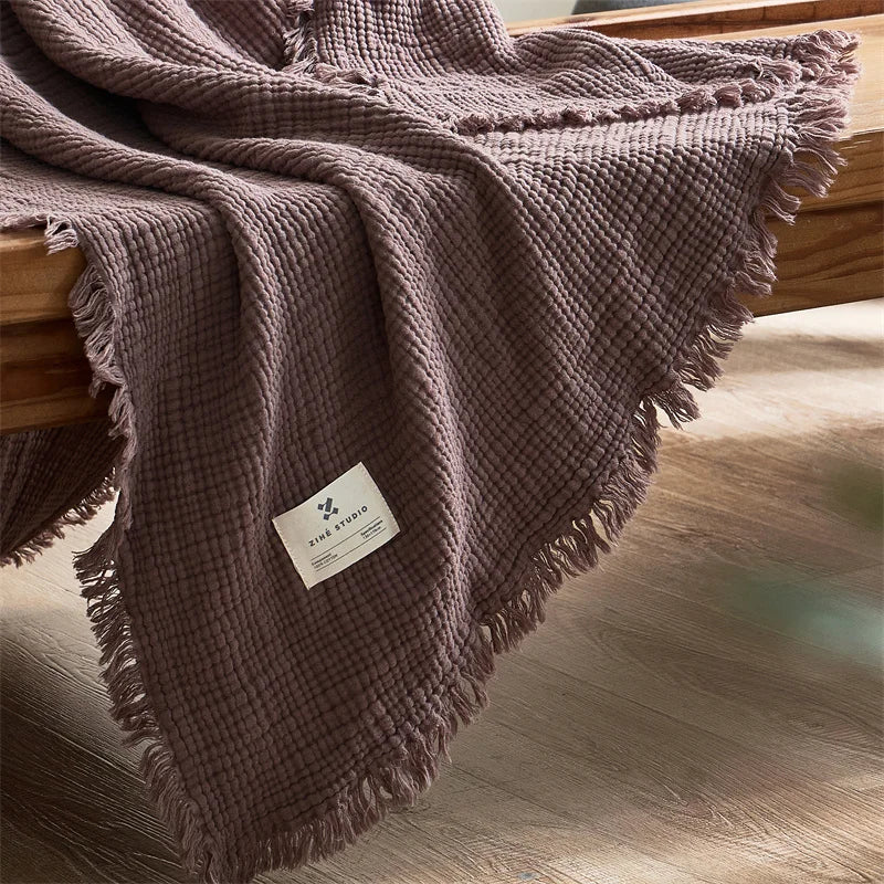 Nogu Throw Blanket – soft Maillard cotton throw with a layered gauze texture, fringe detail, and chic muted colorways, available in two sizes for cozy, stylish comfort.