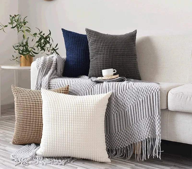 A stylish Warren Pillow Cover displayed on a couch, showcasing its soft corduroy corn grain texture. Available in various colorways and sizes, this square pillow cover adds warmth and elegance to any space. Ideal for home décor enthusiasts, it enhances living areas with a cozy, inviting touch. Please note that the pillow insert is not included.