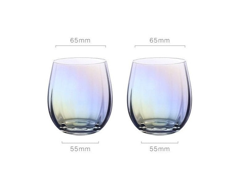 A collection of iridescent glassware from Domus Forge, featuring wine glasses, champagne coupes, decanters, and highball glasses in pastel gradient hues.