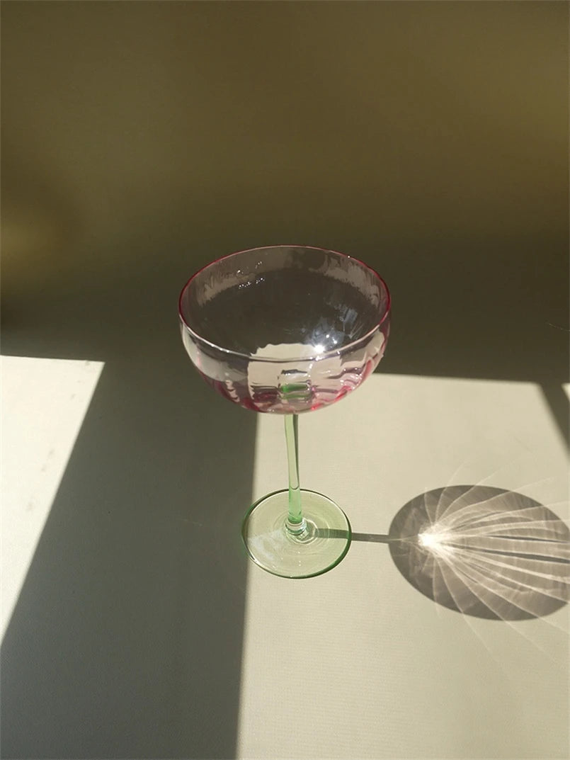 A vibrant collection of Ugo Wine Glasses displayed on a table, showcasing their fun and chic design. Each glass features a colored pastel bowl with a contrasting stem and a fluted shape. Ideal for entertaining, these glasses hold 11 fluid ounces and are perfect for mixing and matching. Designed for home décor enthusiasts, they add a playful yet elegant touch to any bar or dining setting.