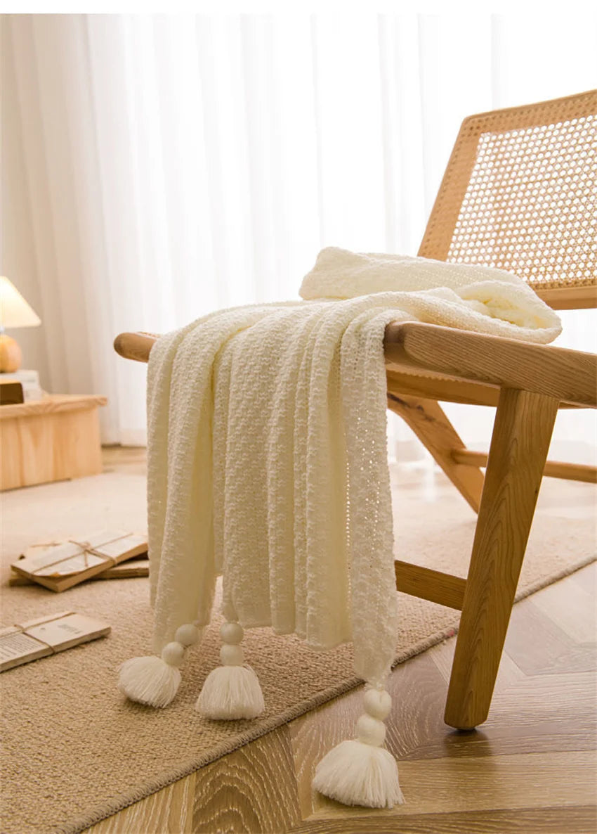 Image of the Soma Throw Blanket, featuring a cozy, soft fleece and cotton blend with a waffled texture. Available in various colorways and three sizes, this throw blanket has elegant tasseled corners and a knitted design, perfect for home décor enthusiasts looking to add comfort and style to their living space.