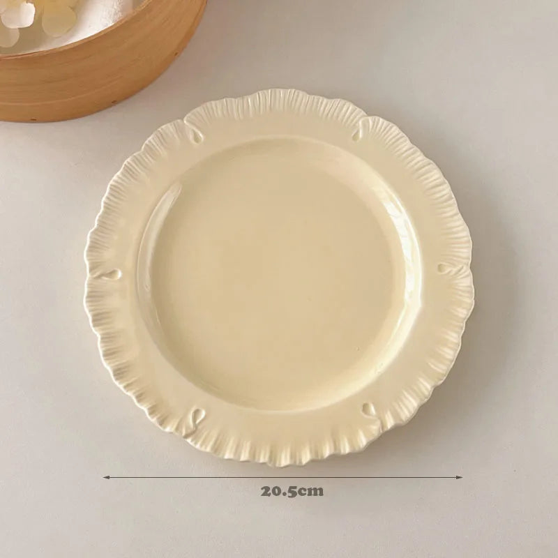 Damian Plate Collection – ceramic plates and bowls with delicate ruffled edges, available in white or cream, combining simple elegance with a soft, feminine touch.