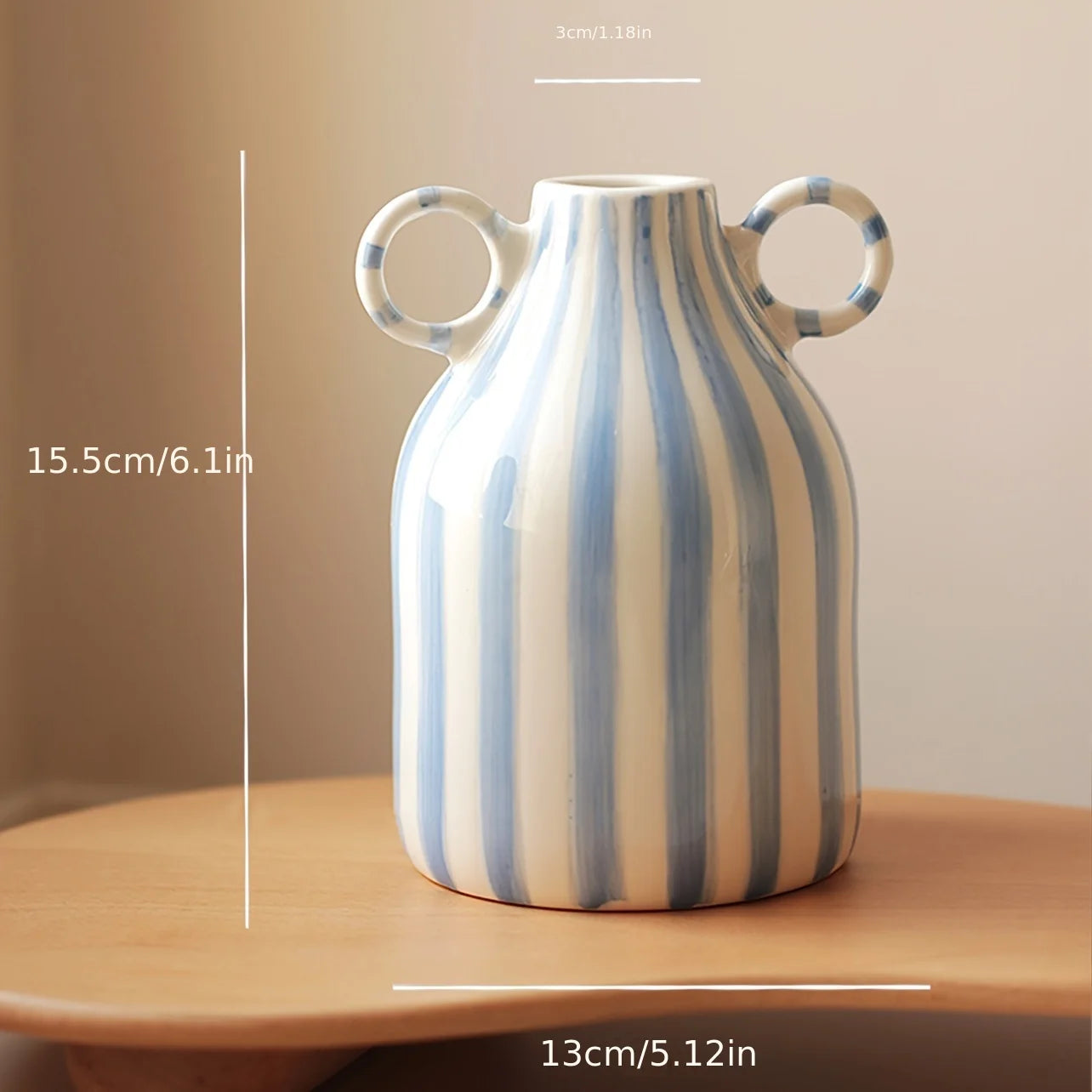 Yug Vase featuring blue and white hand-painted stripes, crafted from durable ceramic. Ideal for home décor enthusiasts, the vase displays flowers or greenery, adding a charming touch to any room.