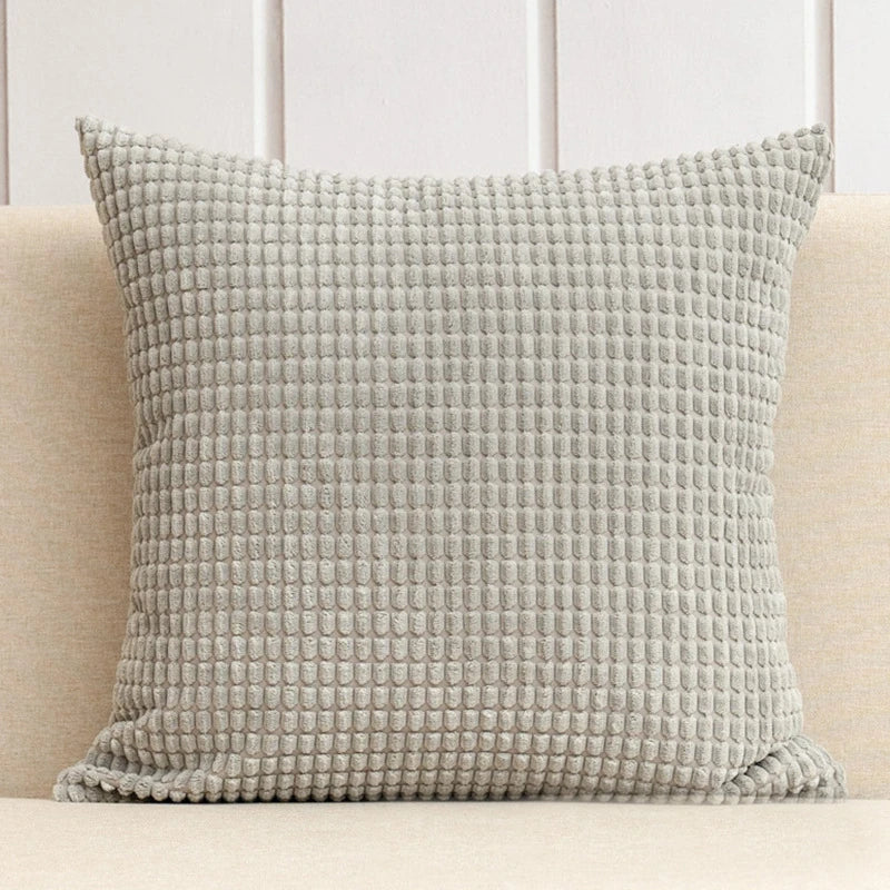 A stylish Warren Pillow Cover displayed on a couch, showcasing its soft corduroy corn grain texture. Available in various colorways and sizes, this square pillow cover adds warmth and elegance to any space. Ideal for home décor enthusiasts, it enhances living areas with a cozy, inviting touch. Please note that the pillow insert is not included.