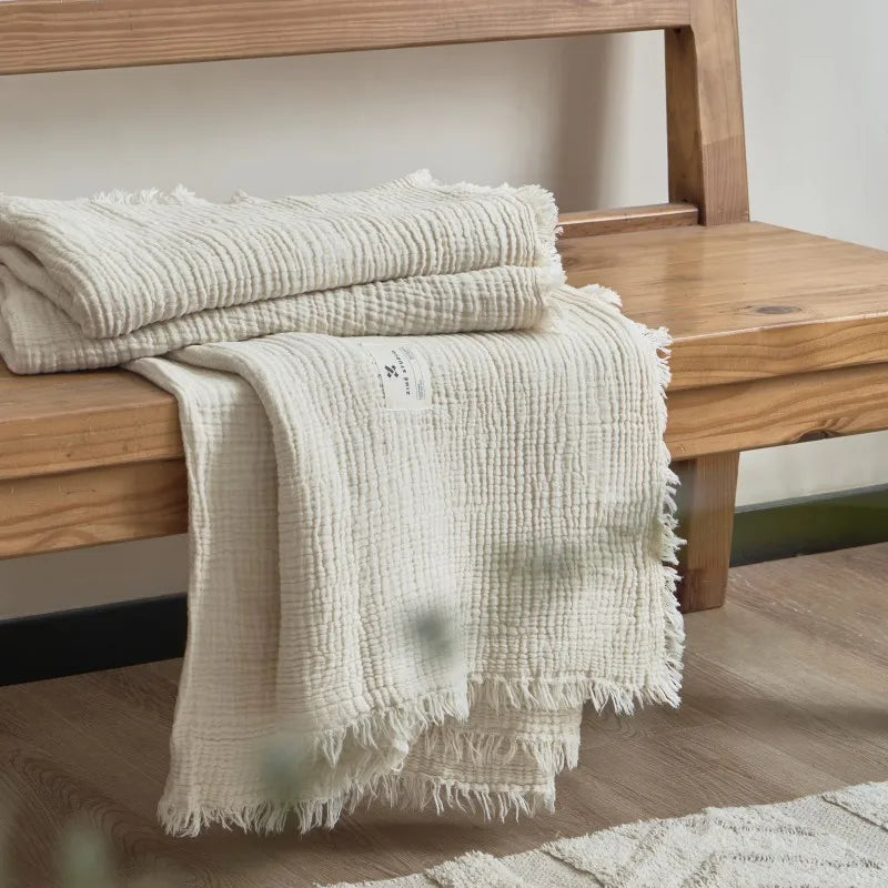 Nogu Throw Blanket – soft Maillard cotton throw with a layered gauze texture, fringe detail, and chic muted colorways, available in two sizes for cozy, stylish comfort.
