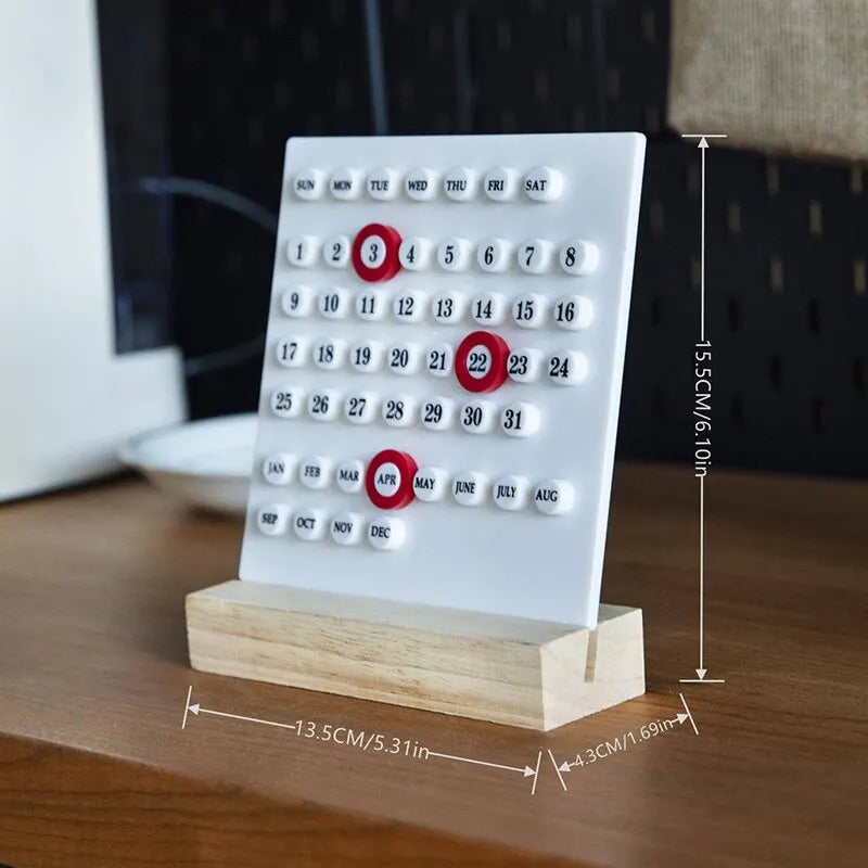 Image of the Callie Calendar, a compact, reusable calendar in black or white with a sleek acrylic design and a natural wooden stand. Features a red marker for highlighting important dates, perfect for organizing spaces like the kitchen or office with a touch of style.