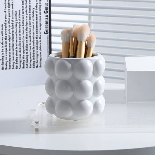 Image of the Vermi Beauty Jar, a ceramic vanity organizer with large beaded details, available in three colorways: white, milk, or silver. This stylish, modern jar is designed for organizing cosmetic brushes and beauty products on a bathroom countertop, ideal for home décor enthusiasts.