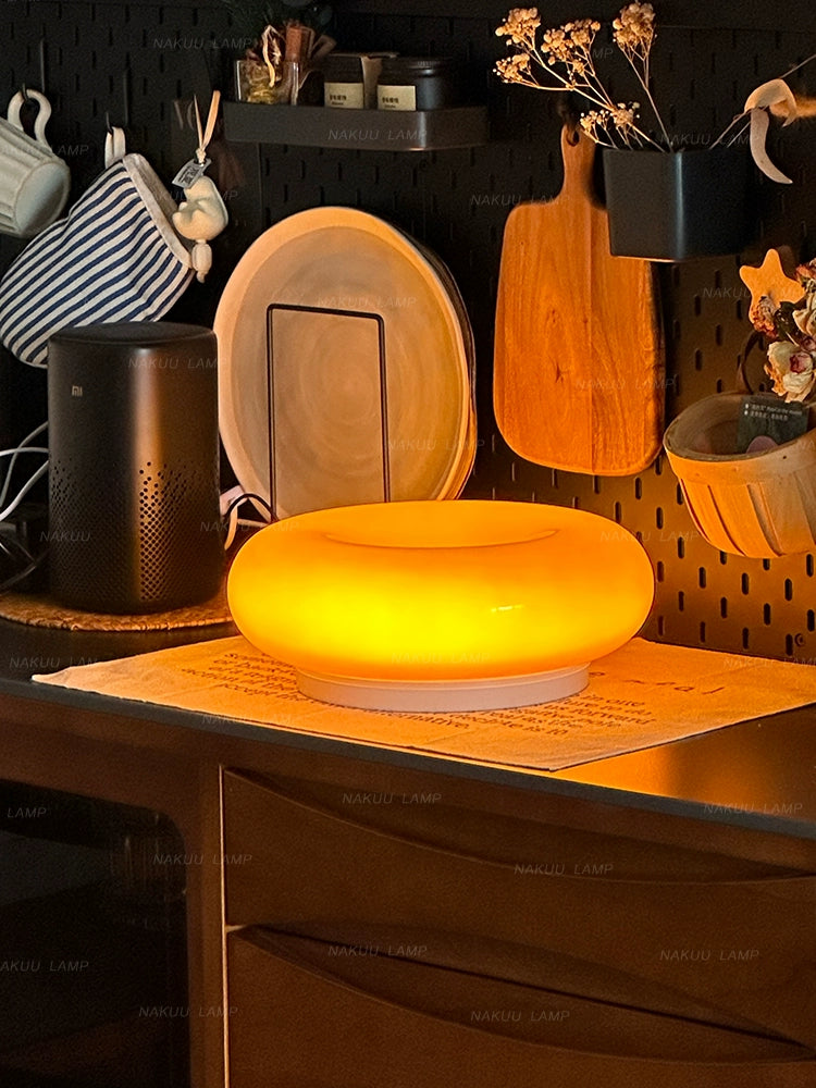 Orange or white doughnut-shaped Roman Lamp - a versatile modern masterpiece for table or wall placement. Glass design adds sophistication to contemporary decor. Illuminate your space with this chic statement piece.