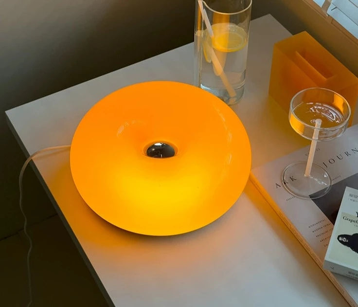 Orange or white doughnut-shaped Roman Lamp - a versatile modern masterpiece for table or wall placement. Glass design adds sophistication to contemporary decor. Illuminate your space with this chic statement piece.