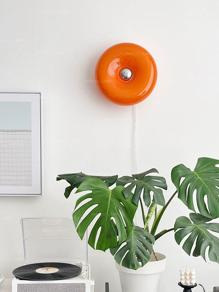 Orange or white doughnut-shaped Roman Lamp - a versatile modern masterpiece for table or wall placement. Glass design adds sophistication to contemporary decor. Illuminate your space with this chic statement piece.