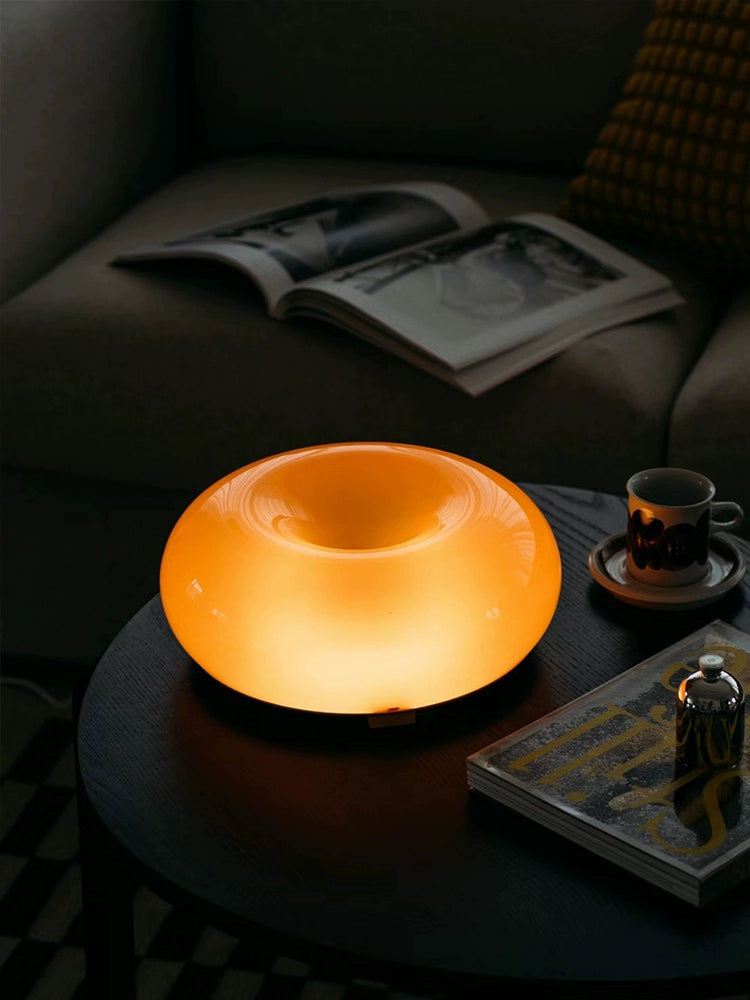 Orange or white doughnut-shaped Roman Lamp - a versatile modern masterpiece for table or wall placement. Glass design adds sophistication to contemporary decor. Illuminate your space with this chic statement piece.