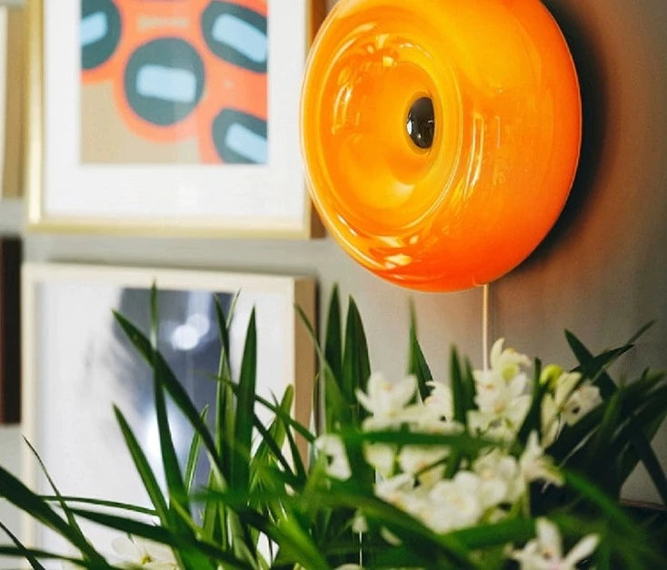 Orange or white doughnut-shaped Roman Lamp - a versatile modern masterpiece for table or wall placement. Glass design adds sophistication to contemporary decor. Illuminate your space with this chic statement piece.