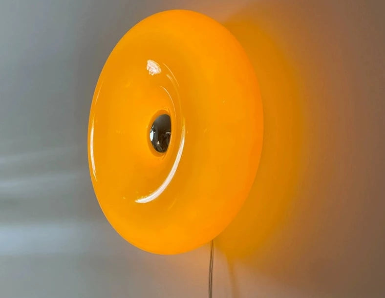 Orange or white doughnut-shaped Roman Lamp - a versatile modern masterpiece for table or wall placement. Glass design adds sophistication to contemporary decor. Illuminate your space with this chic statement piece.