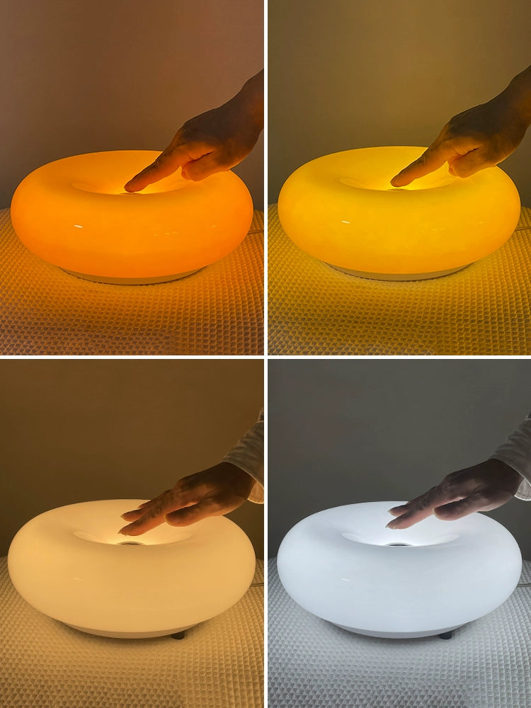 Orange or white doughnut-shaped Roman Lamp - a versatile modern masterpiece for table or wall placement. Glass design adds sophistication to contemporary decor. Illuminate your space with this chic statement piece.