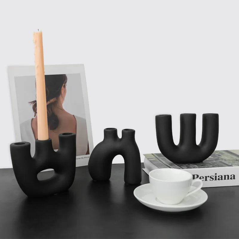 Reese Candle Holder collection - A modern display of ceramic candle holders in organic shapes, available in black and white colorways. The cool rounded shapes create a visually appealing design with four different variations. Elevate your space with these contemporary candle holders for a stylish and unique touch.